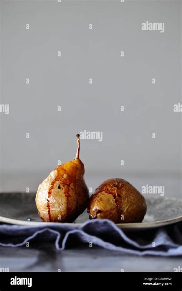 Baked pears on a plate with yogurt and granola.